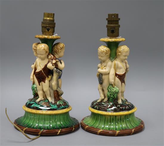 A pair of Minton majolica tazza bases, each modelled with three cherubs (converted as table lamps), H 26cm overall